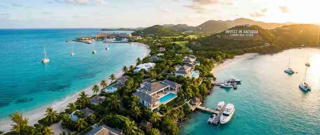 A scenic view of Antigua's coastline with luxury homes and palm trees.