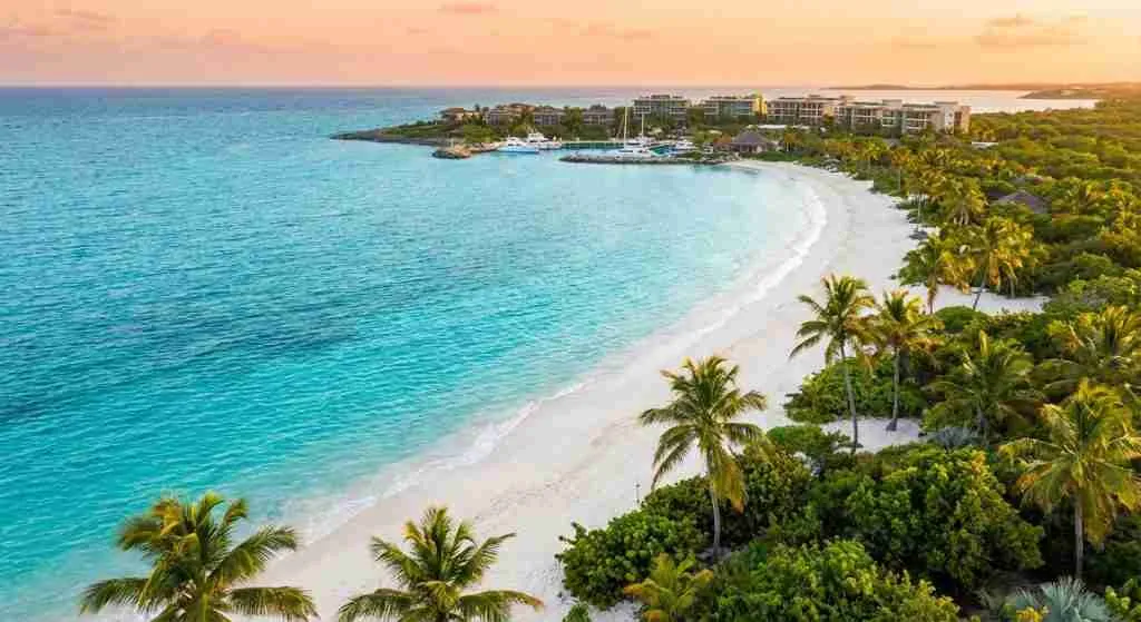 Coastal view of a Caribbean island with clear water and green hills.