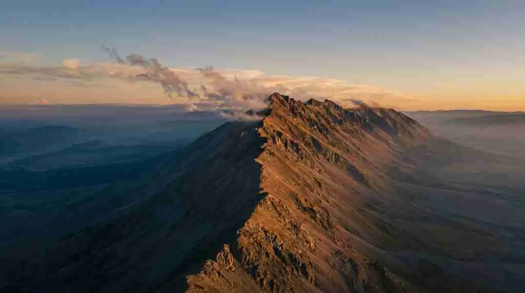 Ein Bergkamm in der Abenddämmerung, die eine Seite golden erleuchtet, die andere im blauen Schatten entlang einer scharfen Trennlinie